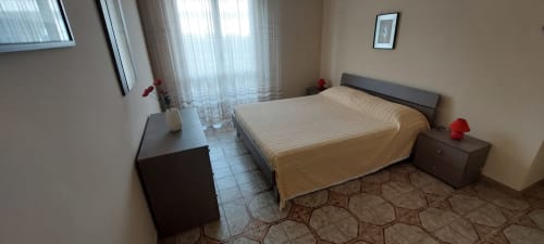 Bright bedroom at Tales of Abruzzo hotel in Atessa with queen bed, nightstands, and sea view windows