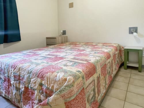 Chambre de l'appartement Le Vallon des Sources avec lit à courtepointe patchwork, mobilier bois et carrelage à Digne-les-Bains