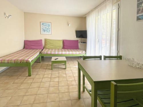 Lumineux séjour de Le Vallon des Sources à Digne-les-Bains avec mobilier vert, coussins roses et balcon