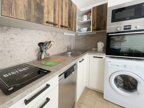 Cuisine moderne de l'appartement Le Vallon des Sources avec armoires en bois, comptoirs en granit et appareils en acier inoxydable