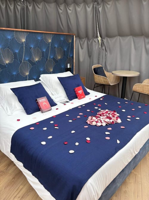 Chambre romantique à l'hôtel Bubble Jade avec linge de lit bleu marine, pétales de roses et tête de lit décorée à Bazouges-la-Pérouse