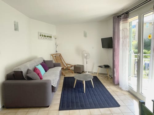 Séjour moderne du Vallon des Sources avec canapé gris, TV, accès au balcon et vue sur les montagnes
