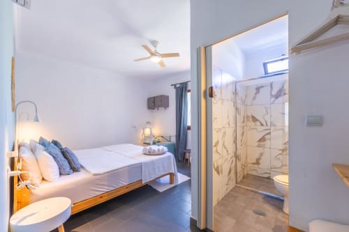 Levante room at Casa de Océano hotel in Tarifa with bed, ensuite bathroom, ceiling fan and modern decor
