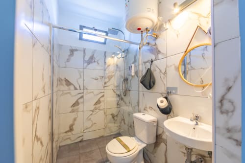 Modern bathroom in Levante room at Casa de Océano hotel in Tarifa with marble tiles, glass shower, and brass fixtures