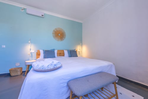 Modern bedroom at Casa de Océano hotel in Tarifa with turquoise accent wall, white bedding, and warm lighting