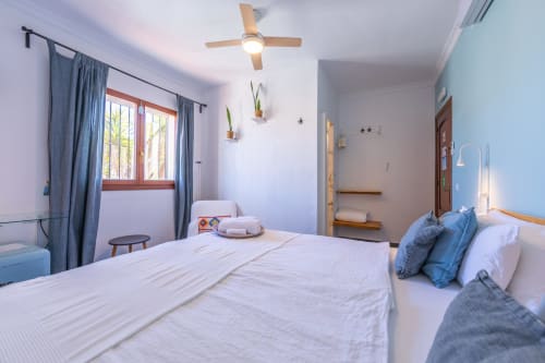 Levante room at Casa de Océano in Tarifa with queen bed, ceiling fan, blue curtains and modern decor