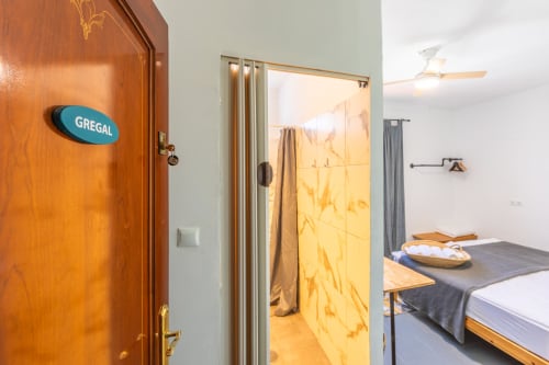 Gregal room at Casa de Océano in Tarifa with wooden door, ensuite bathroom, and bed
