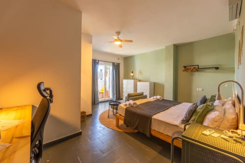 Sirocco room at Casa de Océano hotel in Tarifa with two beds, green walls, ceiling fan, and balcony access