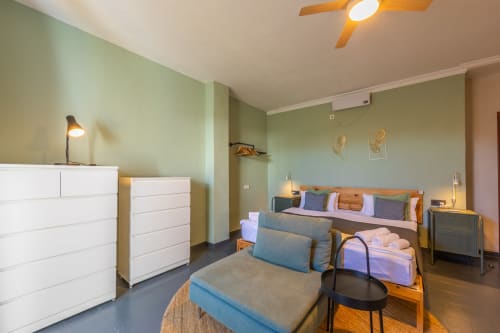 Sirocco room at Casa de Océano hotel in Tarifa with green walls, white furniture, bed with colorful pillows, sitting area