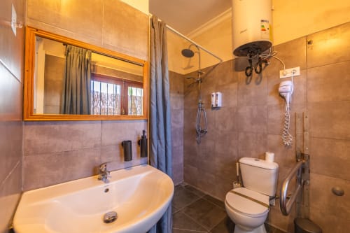 Bathroom in Sirocco room at Casa de Océano hotel, Tarifa with sink, toilet, shower and wooden-framed mirror