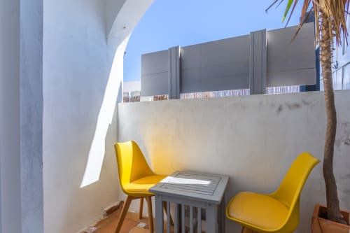 Sirocco room at Casa de Océano in Tarifa features a sunny terrace with yellow chairs and small table overlooking the city.