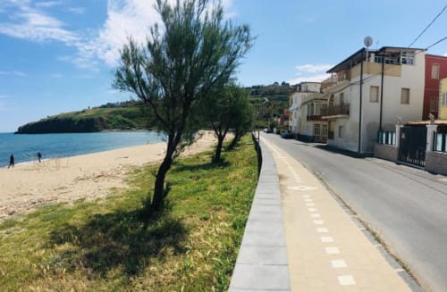 Coastal path at Noemi Holiday House in Agnone Bagni with sandy beach, sea view, and colorful buildings