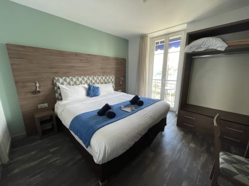 Modern hotel bedroom at Hotel Flots d'Azur Nice with sea view balcony, king bed, and contemporary furnishings