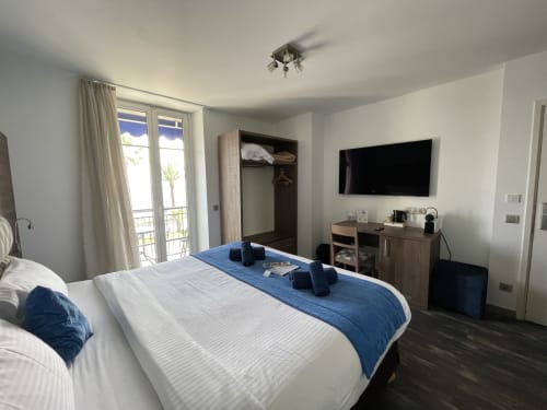 Modern hotel bedroom at Hotel Flots d'Azur in Nice with sea view balcony, flat-screen TV, and contemporary furnishings