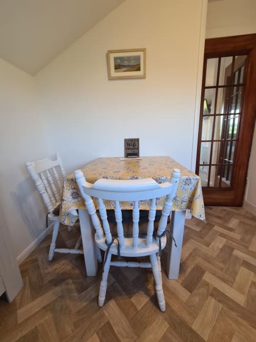 Cozy dining area at 2 Doves Holiday Property in Exeter with round table, white chairs, and floral tablecloth