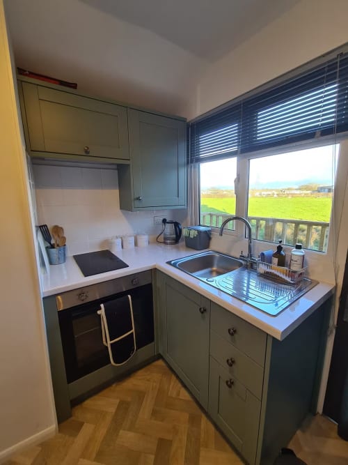 Modern kitchen with sink, cooker, and countryside view at 2 Doves Holiday Property, Exeter