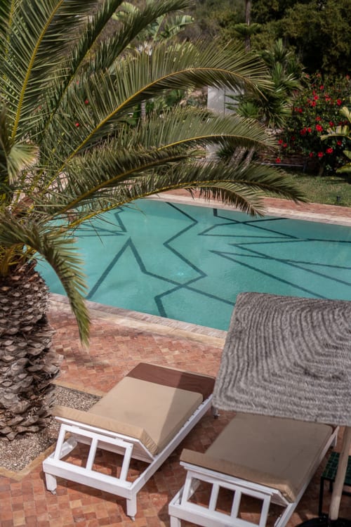 Piscine turquoise ombragée par des palmiers au boutique-hôtel Domaine Belhazar à Essaouira, Maroc