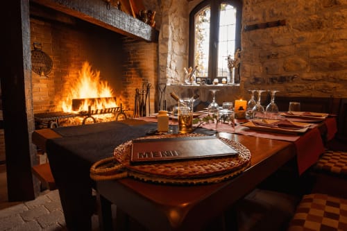 Mesa preparada junto a una parrilla de fuego en un comedor de piedra