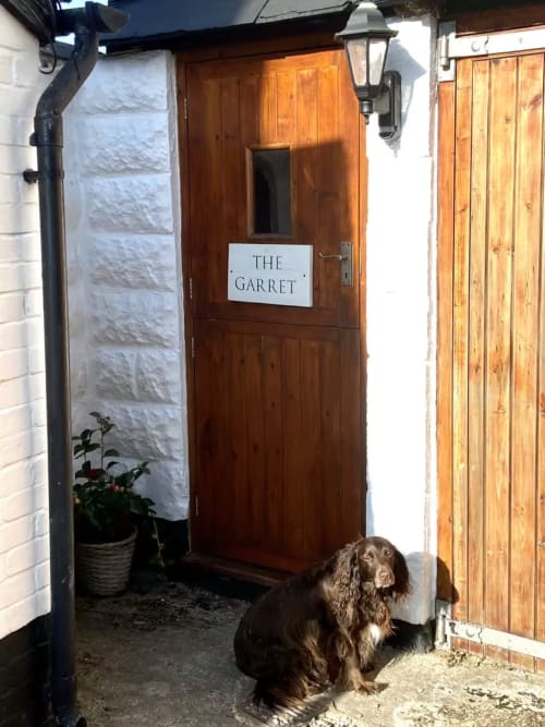 The Garret cottage entrance at 2 Doves Holiday Property in Exeter with brown wooden door and dog sitting outside