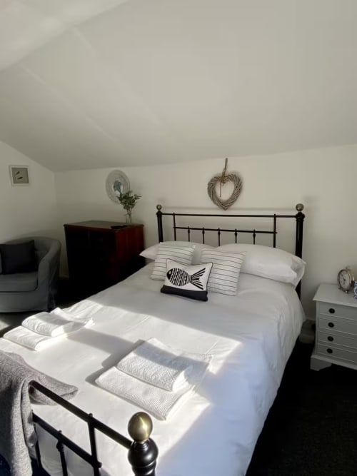 Bright bedroom at 2 Doves Holiday Property, Exeter with metal bed frame, striped pillows and white linens