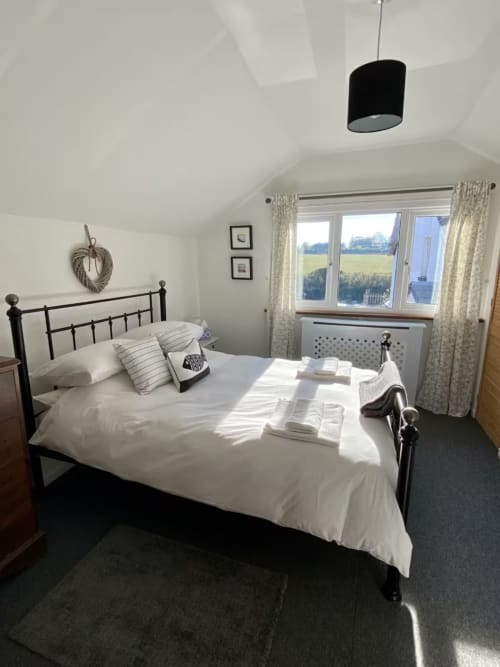 Bright bedroom at 2 Doves Holiday Property in Exeter with black metal bed, white bedding, rural views, and countryside