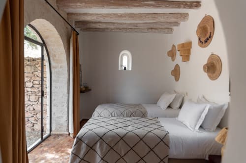 Chambre rustique au Domaine Belhazar à Essaouira avec lits jumeaux, poutres en bois, paniers tissés et fenêtre voûtée