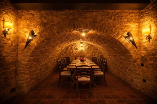 Comedor de piedra con mesa preparada bajo una bóveda iluminada con luz cálida