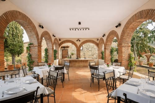 Terraza con arcos de ladrillo y mesas preparadas abiertas al exterior