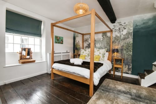 Spacious bedroom at 2 Doves Holiday Property, Exeter with wooden four-poster bed, botanical wallpaper, and dark flooring