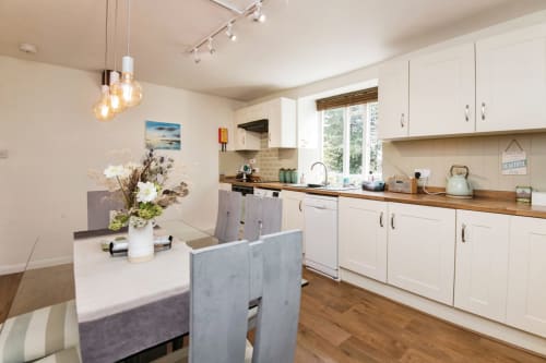 Modern kitchen with white cabinets, wooden countertops, and island seating at 2 Doves Holiday Property in Exeter