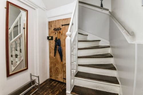 Bright hallway at 2 Doves Holiday Property in Exeter with wooden door, mirror, and white staircase with dark treads
