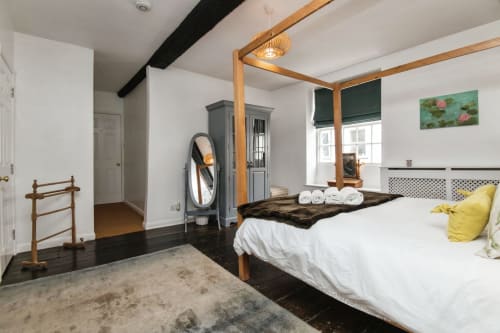 Spacious bedroom at 2 Doves Holiday Property, Exeter with wooden four-poster bed, dark flooring and white walls