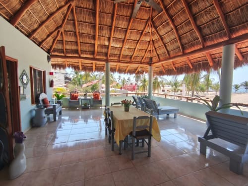 Amplia terraza cubierta en Casa Punta Perula con techo de paja, comedor, tumbonas y vistas al océano de Punta
