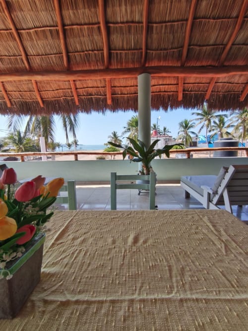 Terraza frente al mar en Casa Punta Perula con techo de palma, vistas al océano, plantas tropicales y zona de descanso con vista a Punta
