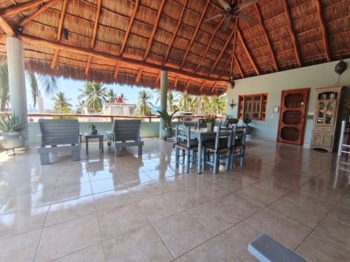 Terraza con vista al océano, palapas de palma, área de comedor y tumbonas en Casa Punta Perula, Punta Perula México