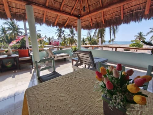 Terraza frente al mar de Casa Punta Perula con tulipanes coloridos, tumbonas y vista al océano desde la Habitación Reina del Mar
