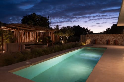 Illuminated lap pool at dusk with lounge areas, stone walls, and gardens at Domaine Belhazar in Essaouira