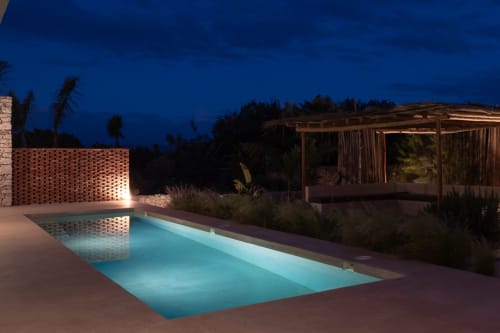 Domaine Belhazar pool at dusk, Essaouira with illuminated brick wall and wooden pavilion