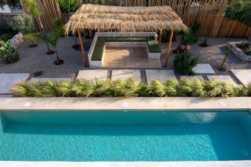 Turquoise pool at Domaine Belhazar in Essaouira with thatched-roof pavilion, lounge seating, and manicured garden