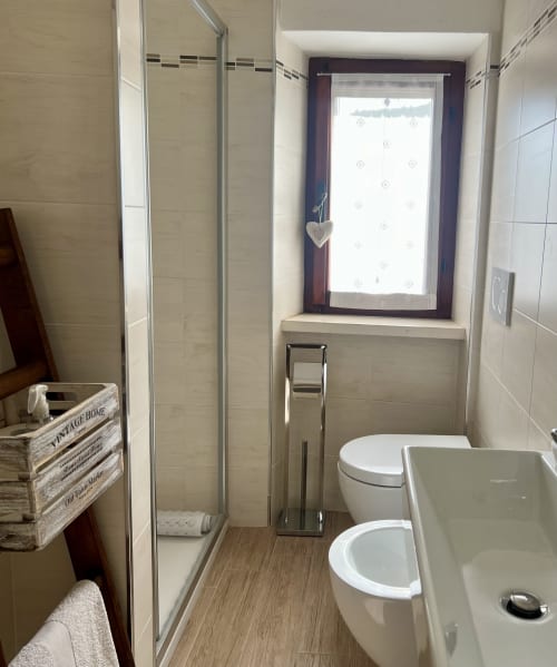 Bagno moderno con doccia, doppi lavandini, WC e finestra con vista a Le Colline della Speranza, Spello Umbria