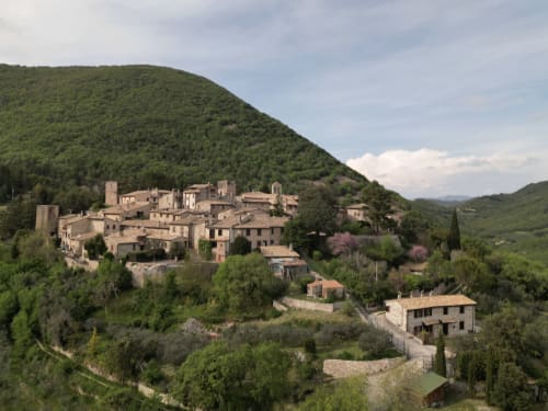 Il borgo medievale di Collepino in Umbria, circondato da dolci colline verdi e cipressi presso Le Colline