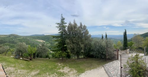 Terrazza panoramica di Le Colline della Speranza con colline umbre ondulate, cipressi e vedute montane da Spello