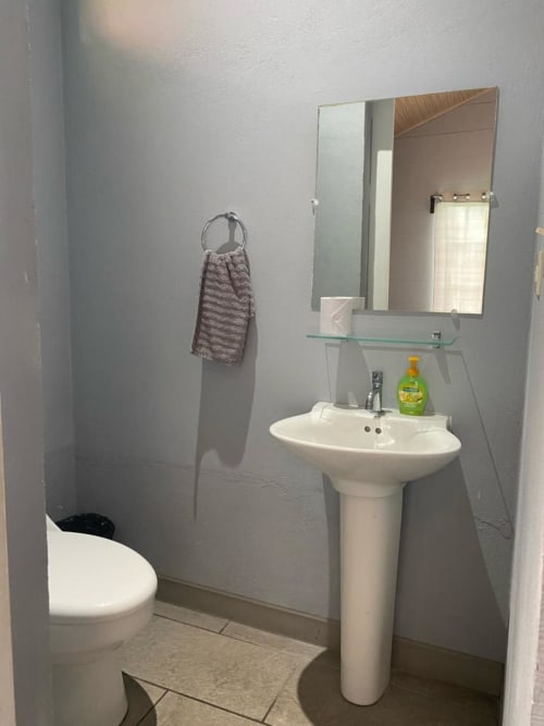 Baño limpio con lavamanos pedestal, espejo e inodoro en villa Cabinas Arenal Home, Costa Rica