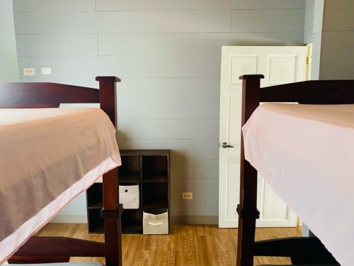 Dos camas gemelas con sábanas rosadas en la habitación de una villa de Cabinas Arenal Home, Costa Rica, con muebles de madera y blanco