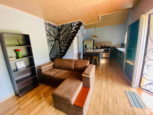Sala moderna de Cabinas Arenal Home con sofá de cuero marrón, techo de madera, arte en escalera y cocina abierta