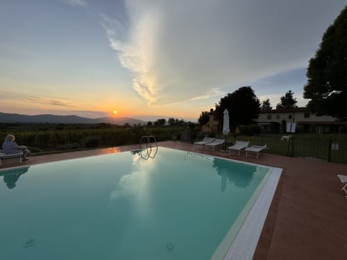Sunset view of turquoise pool at Agriturismo San Jacopo in Reggello, Tuscany, with loungers and countryside landscape