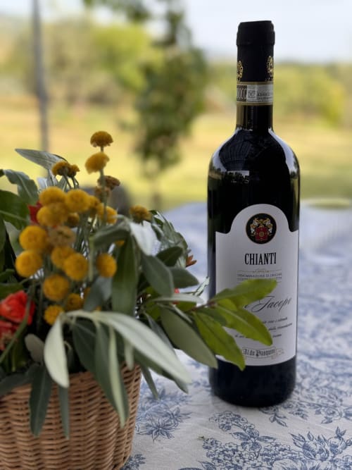 Bottiglia di vino Chianti con fiori selvatici gialli presso l'Agriturismo San Jacopo a Reggello, Toscana