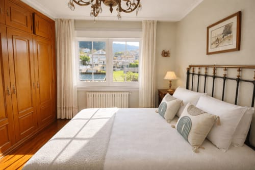 Dormitorio luminoso en  MarySol, Baiona con vista al mar, cama de hierro, armario de madera y vista al jardín