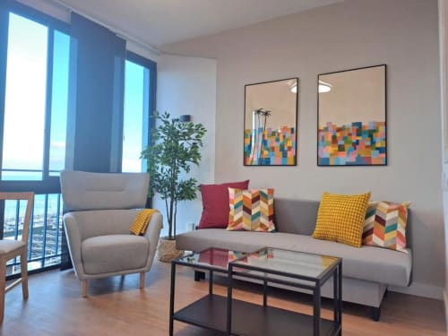 Modernes Wohnzimmer mit grauem Sofa, Sessel und farbenfrohen Kunstwerken in der Bahía Anaga Wohnung, Santa Cruz de Tenerife
