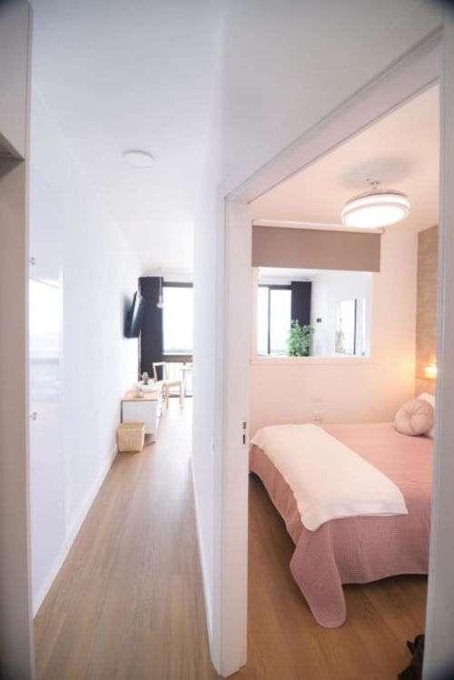 Modernes Schlafzimmer mit Korallenbett, Spiegel, Fenster und Holzböden in der Wohnung Bahía Anaga 703, Santa Cruz de Tenerife